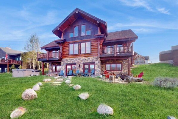 Ein großes Hotel im Chalet-Stil mit mehreren Balkonen, Steinverzierungen und einem Rasen mit Steinen.
