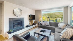 Una sala de estar moderna con chimenea, un ventanal con vistas, un sofá y una mesa de centro.