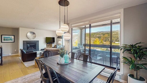 Una sala de estar moderna con comedor, ventanas grandes y chimenea.