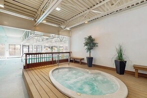 Ein Whirlpoolbereich mit Holzterrasse, Pool und Kübelpflanzen.