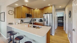 Una cocina moderna con armarios de madera, electrodomésticos de acero inoxidable y una isla central con taburetes.