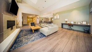 Eine moderne Hotelhalle mit Flachbildfernseher, Kamin, einer Couch, einem Couchtisch und einer Rezeption.