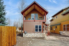 Eine zweistöckige Blockhütte mit Natursteinfundament, einem Balkon und einer Veranda.