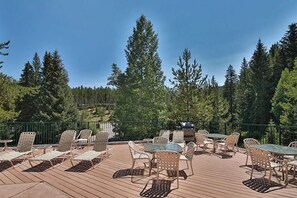 Eine Terrasse mit Gartenmöbeln, darunter Stühle und Tische, umgeben von bewaldeter Landschaft.