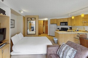 Ein kompaktes Hotelzimmer mit Bett, einer Couch, einer Küchenzeile und einem Spiegel.