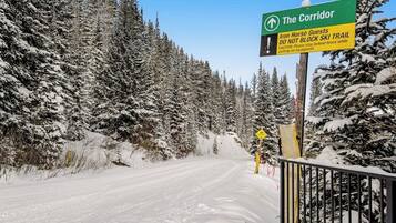 A snow-covered trail with a sign indicating 'The Corridor' and a warning for Iron Horse Guests not to block the ski trail.