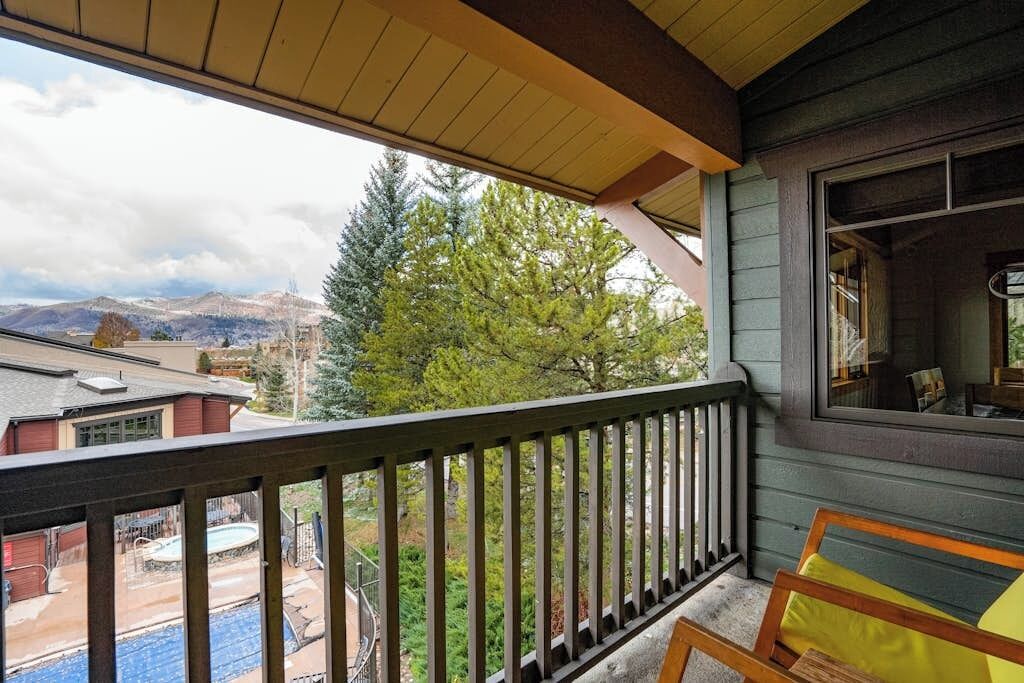 A balcony with a view of a swimming pool and trees.