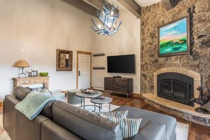 Ein Wohnzimmer mit Kamin aus Stein, Fernseher und einer Couch.