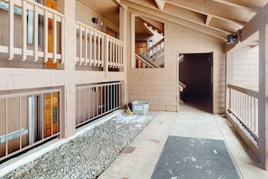 Ein mehrgeschossiges Gebäude mit Holzvertäfelung, einem Kiesweg und einer Metallmülltonne.