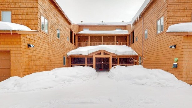 Ein hölzernes Gebäude mit überdachter Eingang und Schnee auf dem Dach.