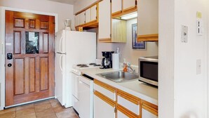 Eine kleine Küche mit Kühlschrank, Herd, Mikrowelle und Spüle.