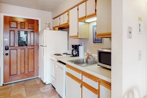 Eine kleine Küche mit Kühlschrank, Herd, Mikrowelle und Spüle.