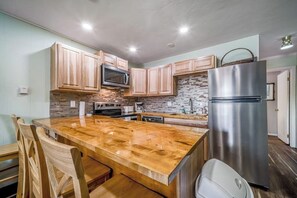 A kitchen with wooden cabinets, a granite countertop, stainless steel appliances, and a stone backsplash. - Second-floor condo with fireplace, hot tub & indoor pool - dog-friendly (Winter Park)