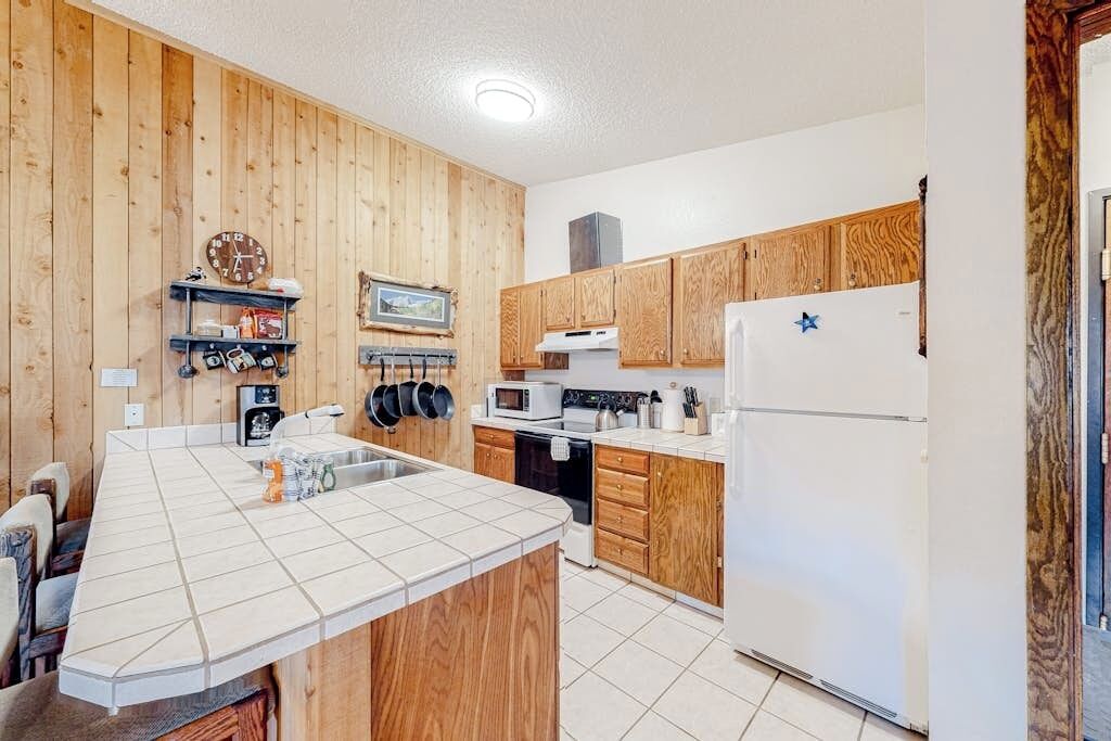 A kitchen with wooden cabinets, a white refrigerator, a microwave, and a stove.