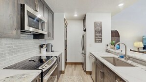 A modern kitchen with stainless steel appliances, a marble countertop, and a wooden backsplash. - Handsome Condo w/WiFi, Deck, Shared Pool, Hot Tub, & Sauna - 2 Miles to Keystone (Keystone)