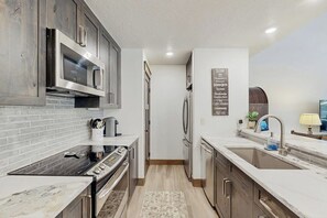 Eine moderne Küche mit Edelstahlgeräten, einer Marmorarbeitsplatte und einer Holzrückwand.