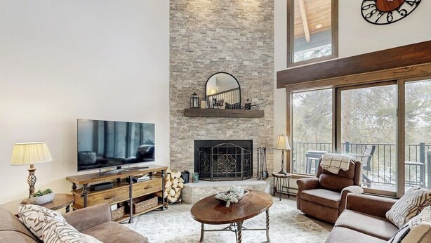 A living room with a fireplace, a television, and a balcony with outdoor furniture. - Handsome Condo w/WiFi, Deck, Shared Pool, Hot Tub, & Sauna - 2 Miles to Keystone (Keystone)
