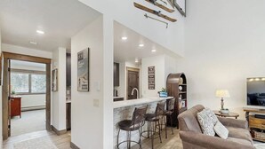 A modern kitchen with a bar area, a dining table, and a sofa in a living room. - Handsome Condo w/WiFi, Deck, Shared Pool, Hot Tub, & Sauna - 2 Miles to Keystone (Keystone)