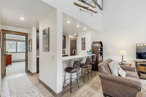 Eine moderne Küche mit Barbereich, einem Esstisch und einer Couch im Wohnzimmer.