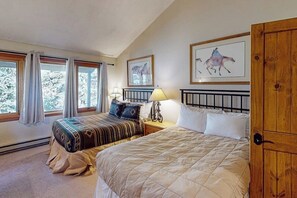 A bedroom with two beds, a wooden wardrobe, and framed artwork on the wall. - Mountain view condo with a wood-burning fireplace - W/D, pool, & hot tub access (Dillon)