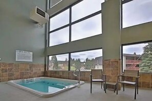 Ein Wellnessbereich mit Pool, Liegestühlen und großen Fenstern.