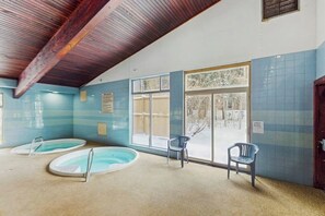 An indoor swimming pool area with two pools, chairs, and a wooden ceiling. - Bright, welcoming condo with pool, hot tub, gas fireplace, fitness room, balcony (Winter Park)