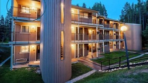 Un hôtel à plusieurs étages, doté d’une façade en bois, de balcons et d’une entrée bien éclairée.