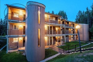 Ein mehrstöckiges Hotel mit Holzfassade, Balkonen und einem gut beleuchteten Eingang.