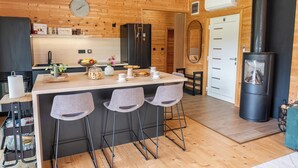 Une cuisine moderne avec des murs en bois, un îlot central doté de tabourets de bar, un four encastré et un poêle à bois.