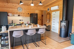 Eine moderne Küche mit Holzwänden, einer zentralen Kochinsel mit Barhocker, einem Einbauofen und einem Kaminofen.
