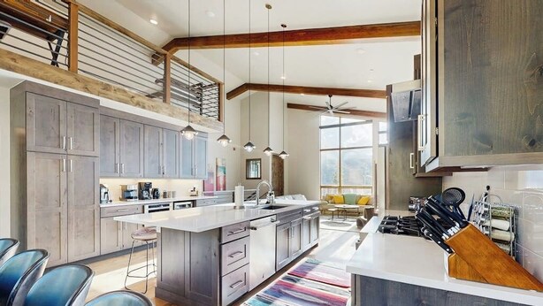 A modern kitchen with a large island, built-in appliances, and a dining area with a view. - Luxury home w/ private hot tub, great views & convenient location (Winter Park)