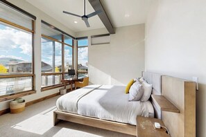 Ein modernes Schlafzimmer mit einem großen Bett, einem Schreibtisch und Blick auf die Stadt.