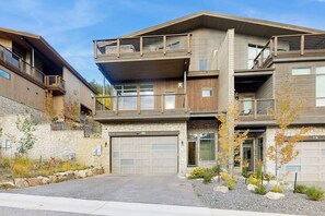 Un moderno edificio residencial de varios pisos con garaje, balcones y fachada de piedra.