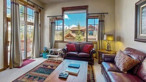 A living room with a sofa, coffee table, and a view through large windows. - Spacious home w/ kitchen, wifi, great views, deck & convenient location (Winter Park)