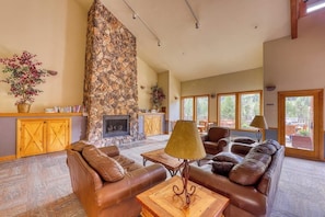 A spacious living room with a stone fireplace, leather sofas, and large windows. - Walk to the Slopes, Amazing Ski Area Views, Shared Hot Tubs Too (Keystone)