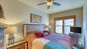 Ein Schlafzimmer mit Bett, Deckenventilator, Fenster und Fernseher.
