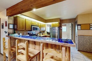 Eine Küche mit Holzausstattung, einer Mikrowelle, einem Kühlschrank und einer Bar mit einer blau gefliesten Arbeitsfläche.