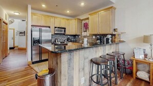 Una cocina moderna con armarios de madera, electrodomésticos de acero inoxidable y una isla central con taburetes.