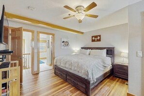A bedroom with a wooden bed, a ceiling fan, a TV, and a wooden cabinet. - Sunny & Spacious Condo in Downtown Dillon, Fireplace, WiFi (Dillon)