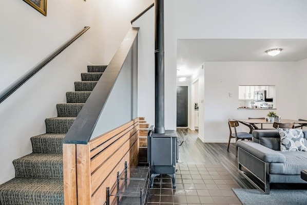 Eine Treppe mit einer Holzhandläufe, ein graues gepolstertes Sofa und ein Küchenbereich im Hintergrund.