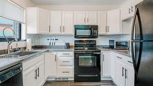 A modern kitchen with white cabinets, a black refrigerator, a microwave, an oven, and a dishwasher. - Two-Level Condo w/ Mountain View, Wood Stove, WiFi, Laundry & Central Location (Pagosa Springs)
