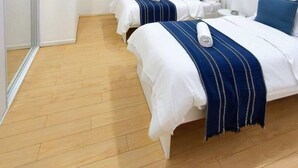 A hotel room with two beds, a shower area, and a wooden floor.