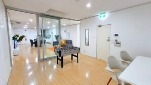 A modern indoor space with a foosball table, a white table, and a glass partition.