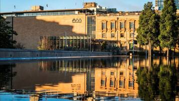 A building with a reflective water body in front, featuring a mix of modern and classical architecture.