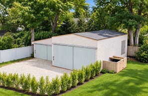 A single-story building with a flat roof, a covered garage, and a small shed. - All New July 2026  5-bedroom house Village of East Hampton W?Pool, Walk to town, (East Hampton)