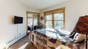 Une chambre à coucher avec un lit, une télévision, une lampe et une fenêtre avec des stores.