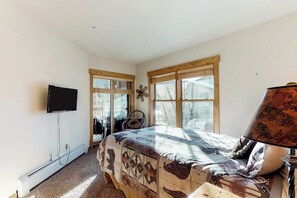 A bedroom with a bed, a TV, a lamp, and a window with blinds. - Corner condo with hot tub & private washer/dryer - steps from the slopes (Keystone)