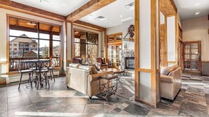 A spacious living area with a fireplace, large windows, and a stone accent wall. - Spacious, resort condo w/private balcony, shared pool & hot tub. Walk to slopes (Keystone)