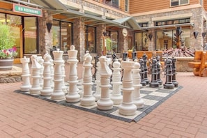 A chessboard with chess pieces arranged in a game setup, a sign for restrooms, and a building with stone facade and large windows. - Newly built townhome with hot tub, decks & gas fireplace - walk to lifts (Keystone)