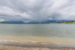 A lake with a shoreline, distant mountains, and buildings in the background. - Newly built townhome with hot tub, decks & gas fireplace - walk to lifts (Keystone)